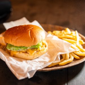 A juicy burger with fries on a wooden plate